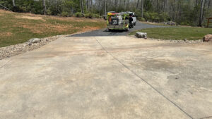 concrete cleaning services being performed on a driveway with a specialized trailer and equipment visible in the background