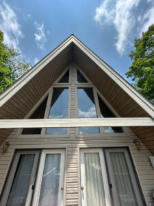 house with large windows and tan siding showing no visible maintenance work being done